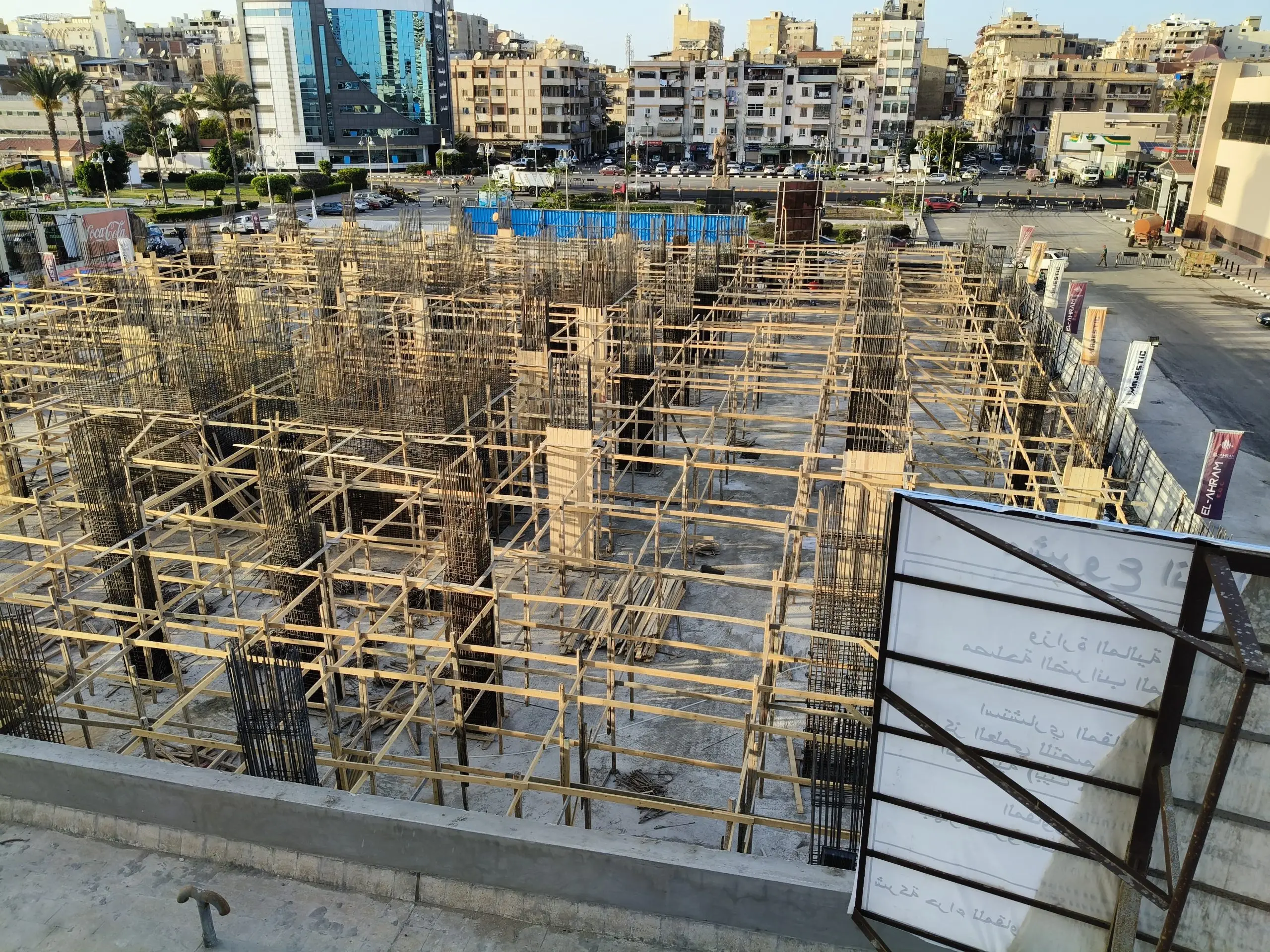 Concrete building construction site with steel rebar and wooden framework at DiamoNest Tower in urban cityscape – موقع بناء خرساني لبرج ديامونيست مع حديد التسليح والقوالب الخشبية وسط المدينة.