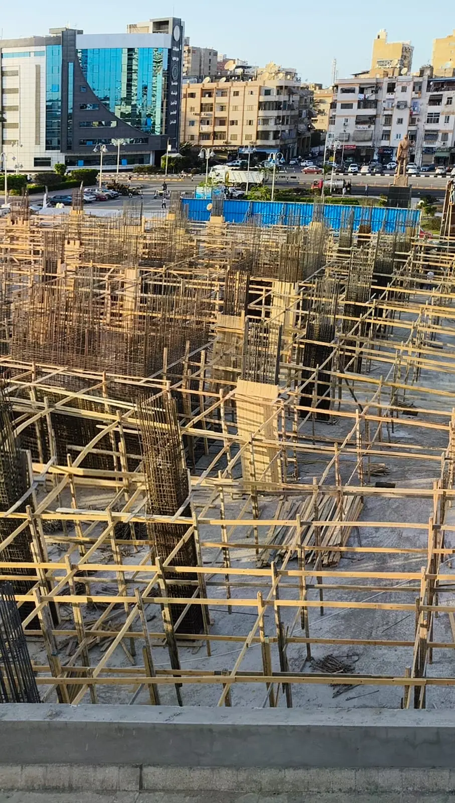 Concrete column rebar with timber formwork in early construction phase at DiamoNest Tower near residential area – حديد تسليح الأعمدة مع شدات خشبية في المرحلة المبكرة للبناء قرب المنطقة السكنية ببرج ديامونيست.