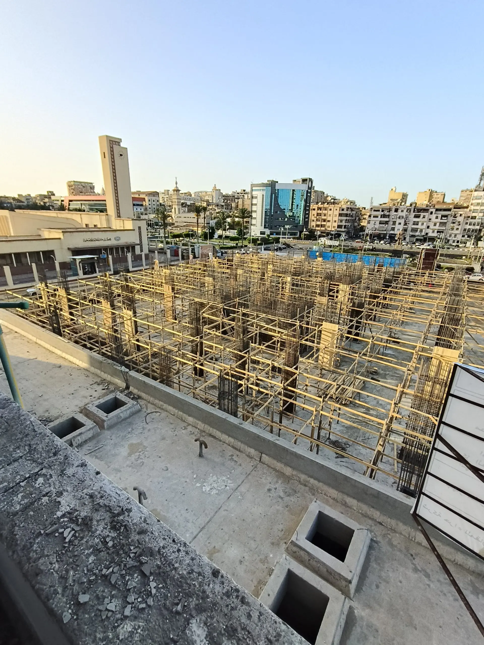 Concrete columns and rebar framework at DiamoNest Tower city construction site – أعمدة خرسانية وحديد تسليح في موقع بناء برج ديامونيست بالمدينة.